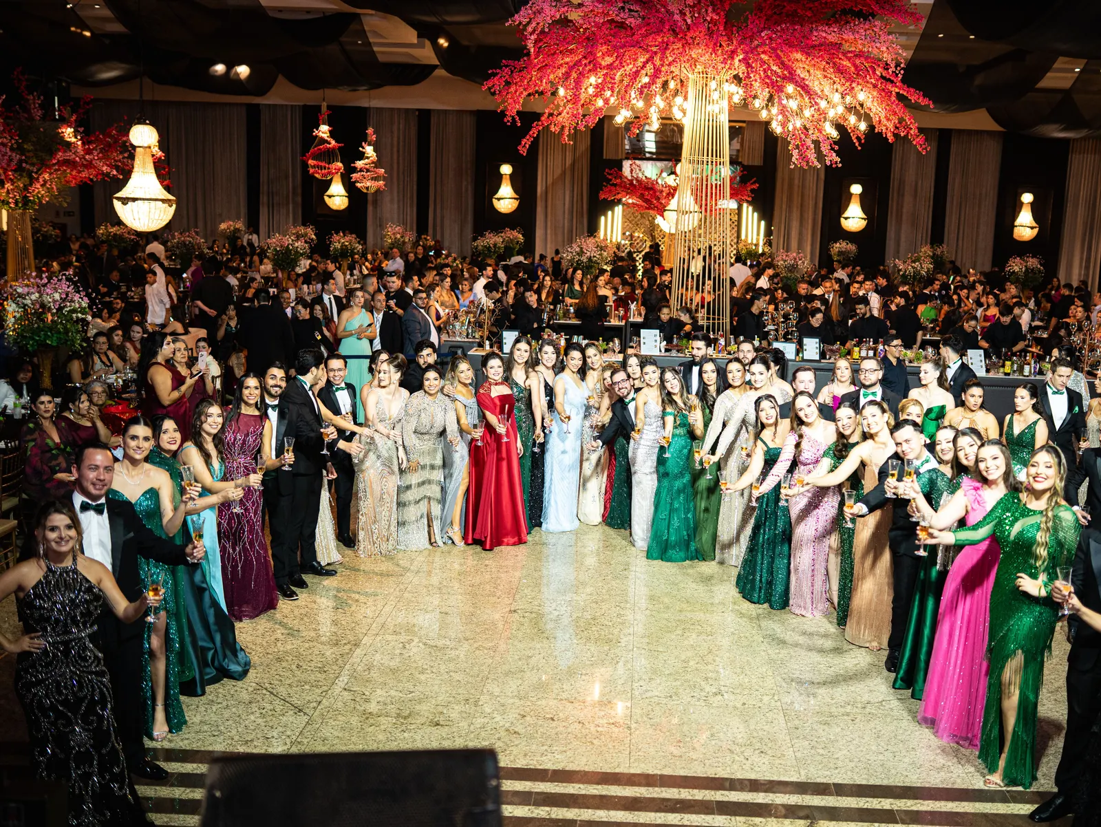 A turma reunida no salão de um baile de gala Monteiro, sob árvores de flores vermelhas