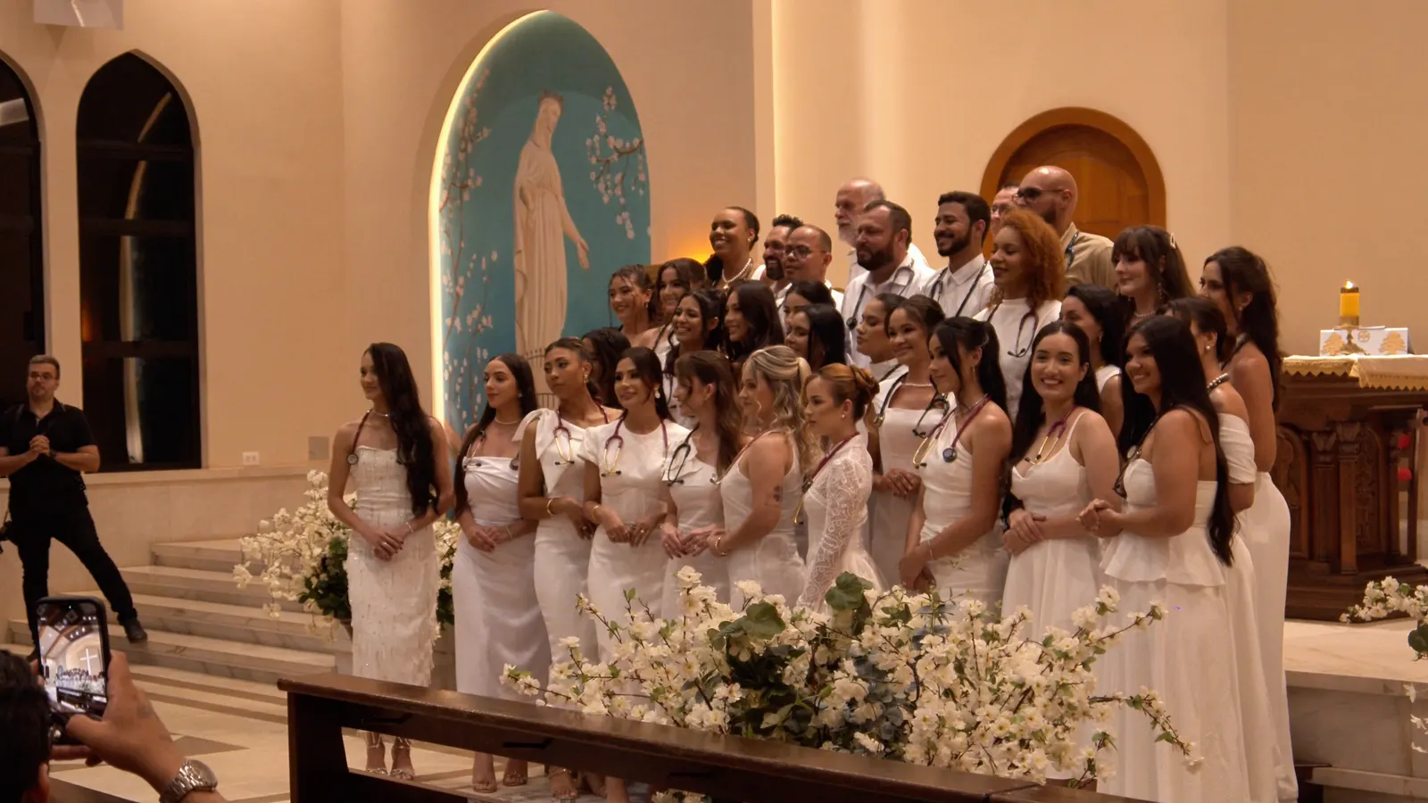 Formandos de Medicina de branco diante do altar na missa de formatura